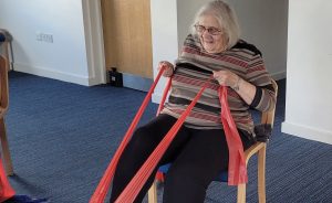 Seated exercise class Waddesdon participant doing a leg exercise with a resistance band